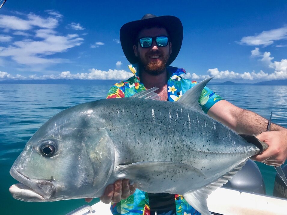 Man wearing a Hawaiin shirt presenting his trevally fish during reef fishing