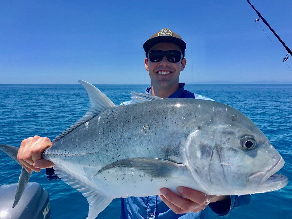 male angler showing his trevally catch 