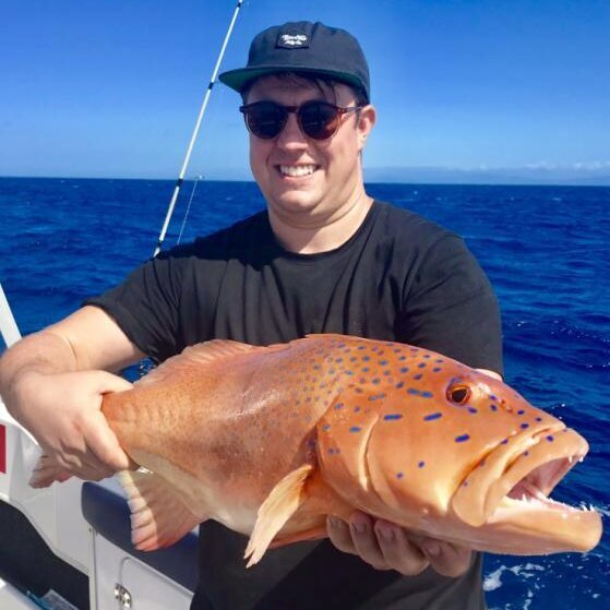 male angler holding a large coral trout